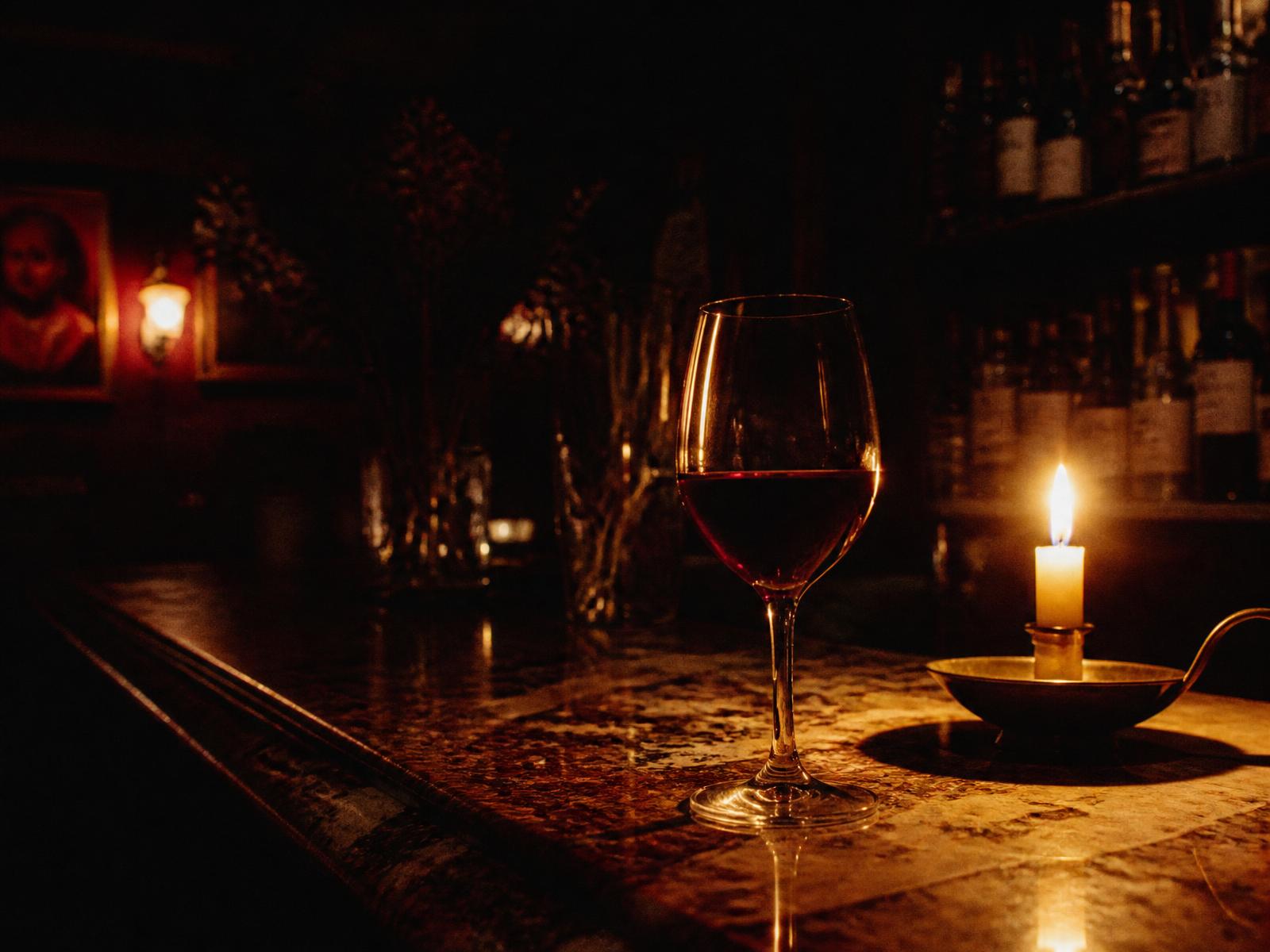 Et glass rødvin i levende lys på en vinbar om kvelden